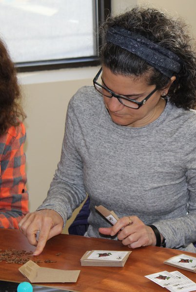 A volunteer helps create milkweed seed packets. Photo: Land Trust.