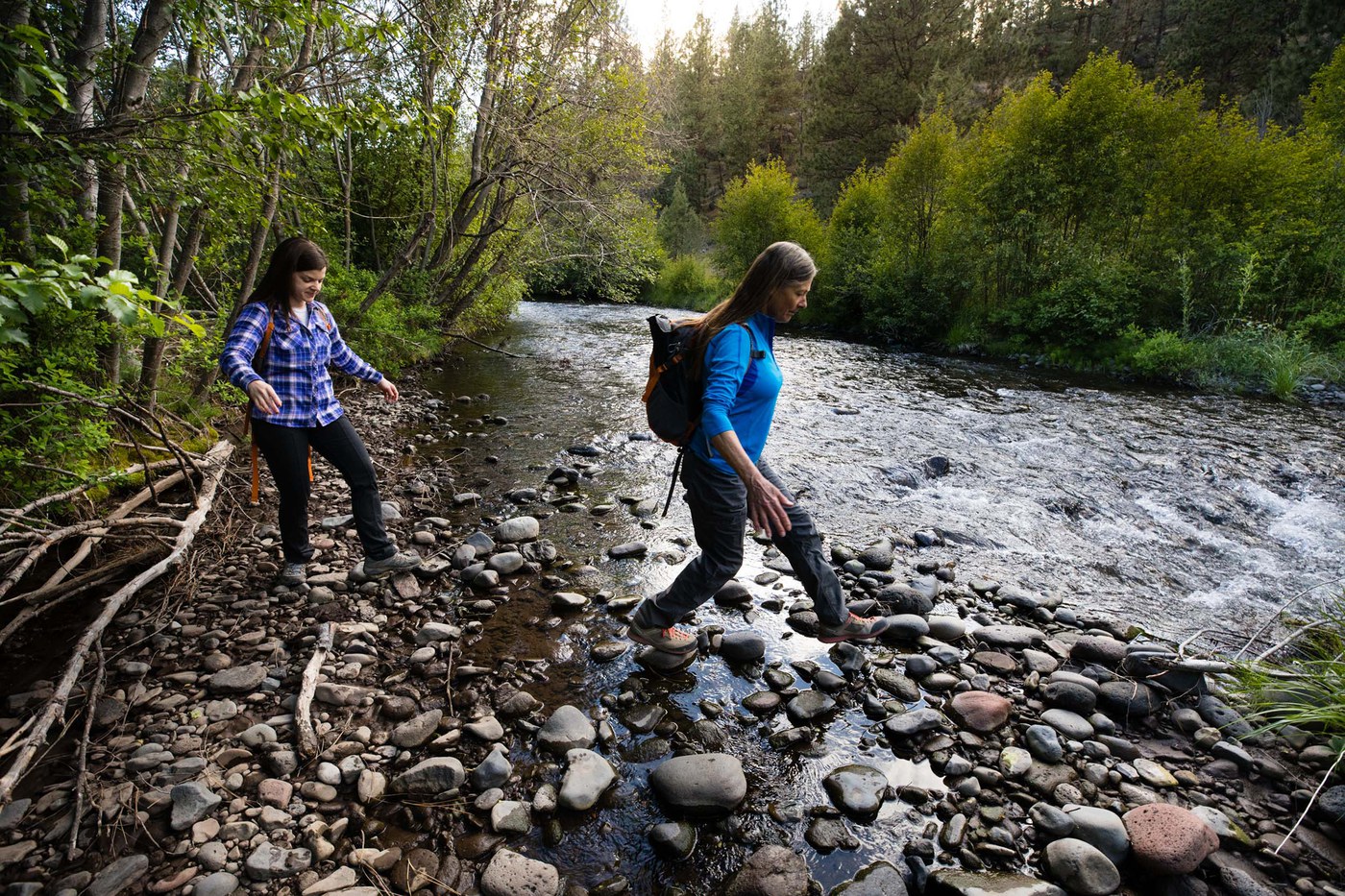 Women hike across stones at Whychus Creek. Photo: Tyler Roemer