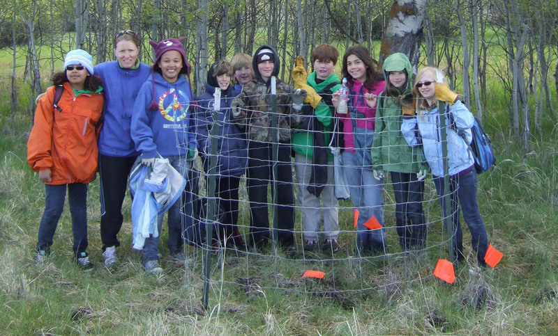 Students from Cascades Academy smile for a photo while working to cage aspen. Photo: Land Trust.