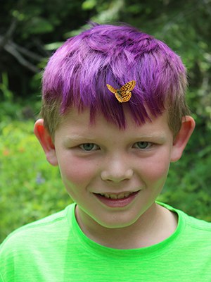 Eli and a butterfly soak in the sunshine. Photo: Land Trust.
